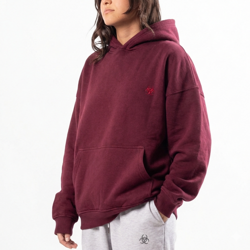 Person wearing a maroon hoodie with a small logo on a white background